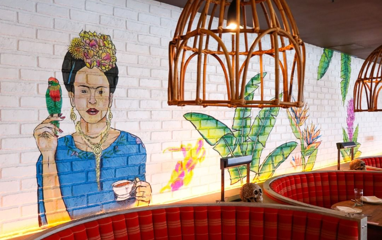 Modern Asian restaurant interior with warm lighting, decorative woven pendant lamps, wooden tables, and open kitchen area